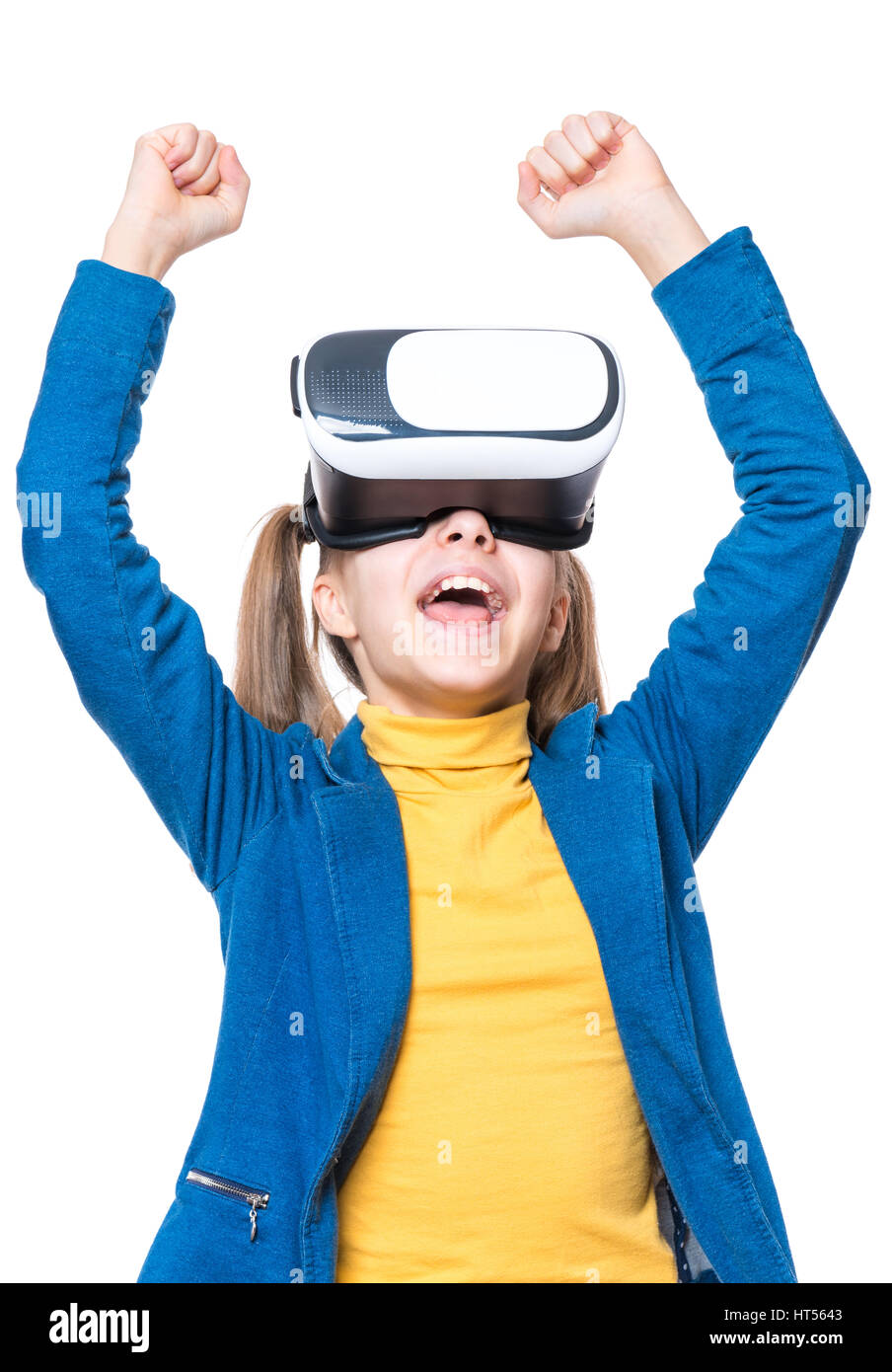 Happy little winner girl wearing virtual reality goggles watching movies or playing video games, isolated on white background. Victory screaming cheer Stock Photo