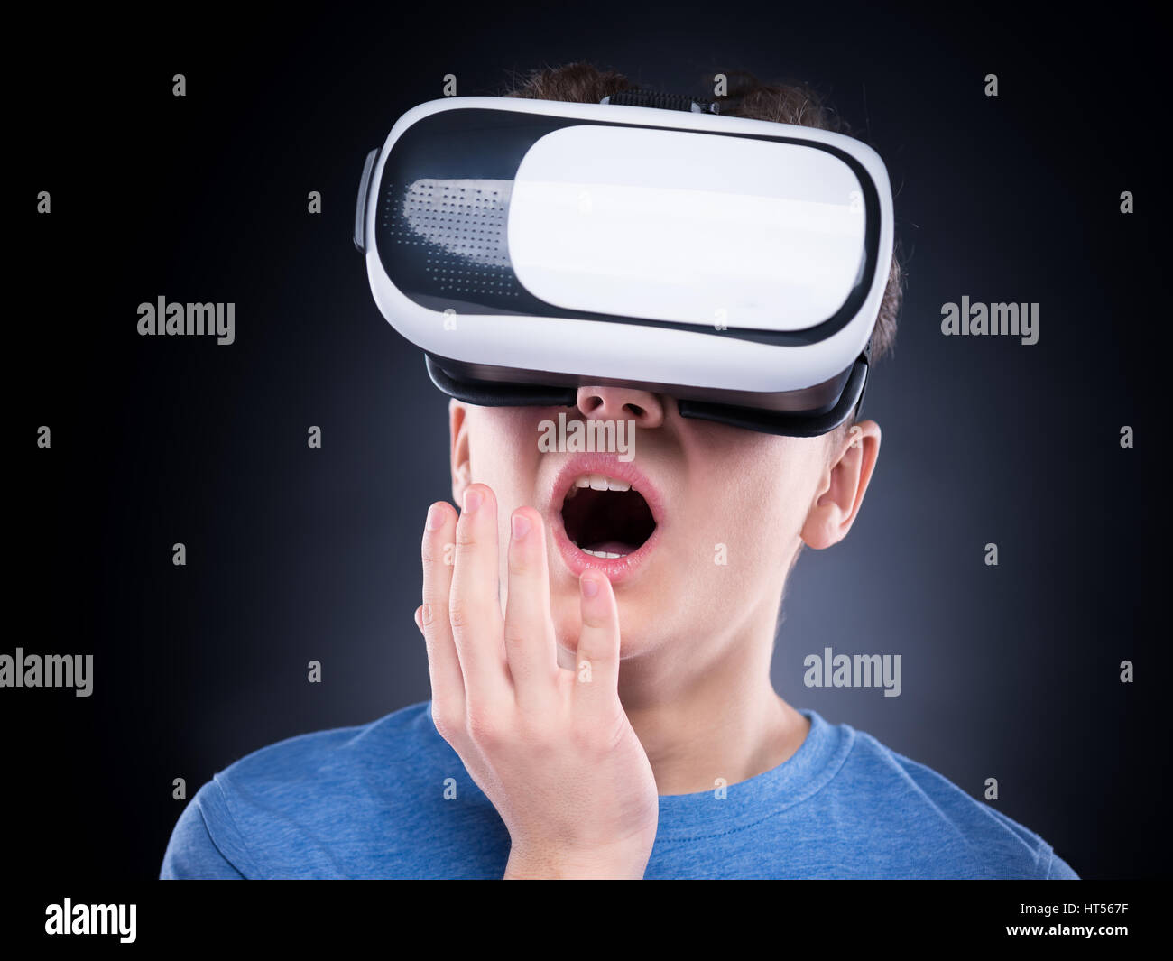 Amazed teen boy screaming, wearing virtual reality goggles watching movies or playing video games. Surprised teenager looking in VR glasses and shouti Stock Photo