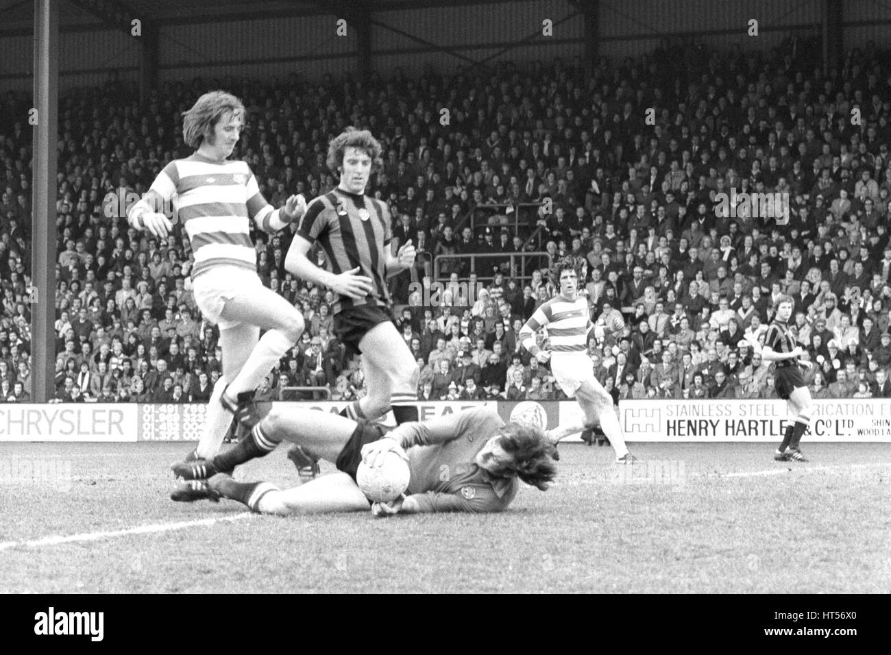 Manchester City goalkeeper Joe Corrigan gets a safe hold on the ball as he clutches it from the feet of QPR striker Stan Bowles, during this afternoon's League Division One match at Loftus Road. The City player in the centre is Tommy Booth. An 81st minute header from Dave Webb clinched victory for the home side. Stock Photo