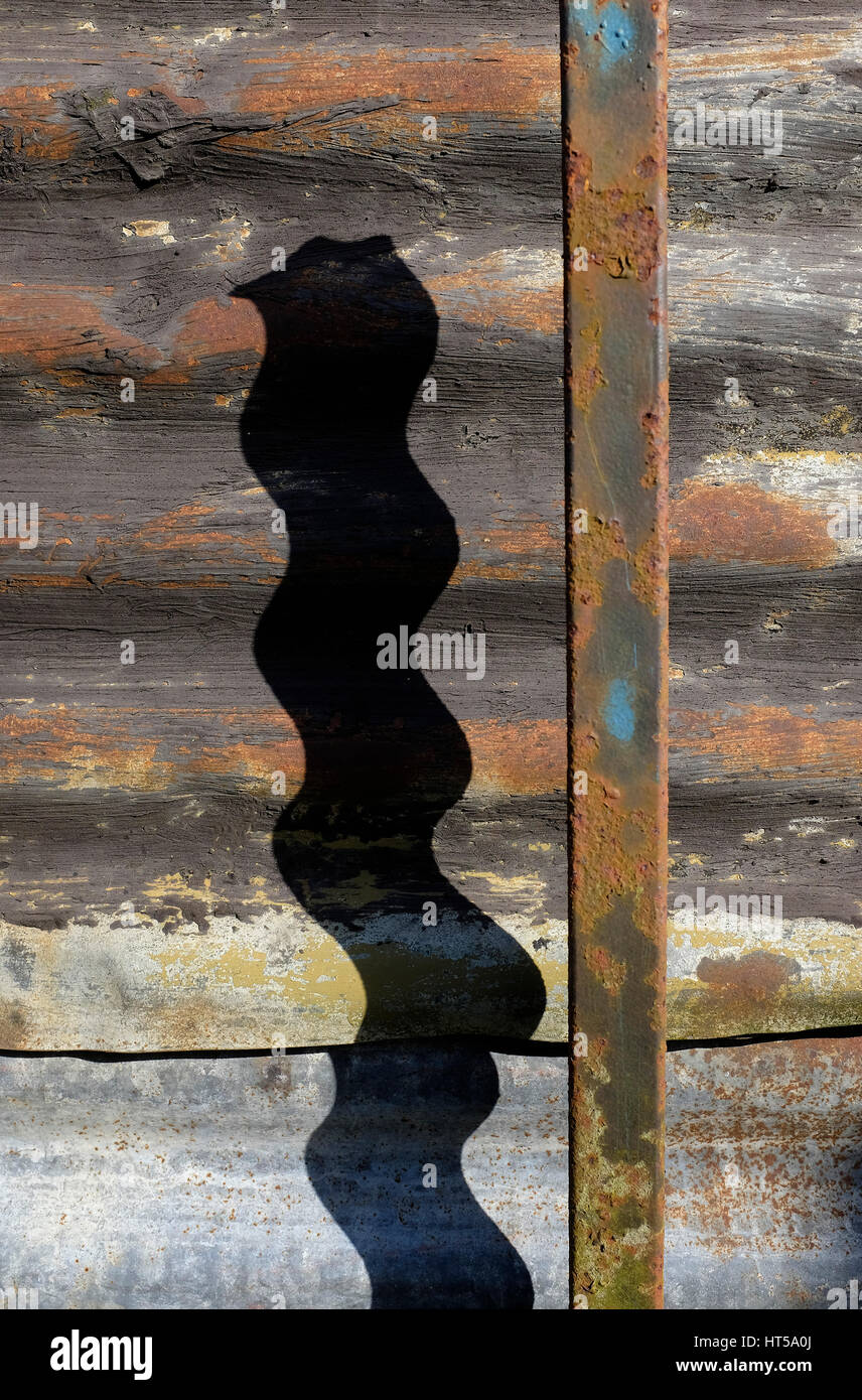 shadow of metal pole on corrugated iron shed wall Stock Photo