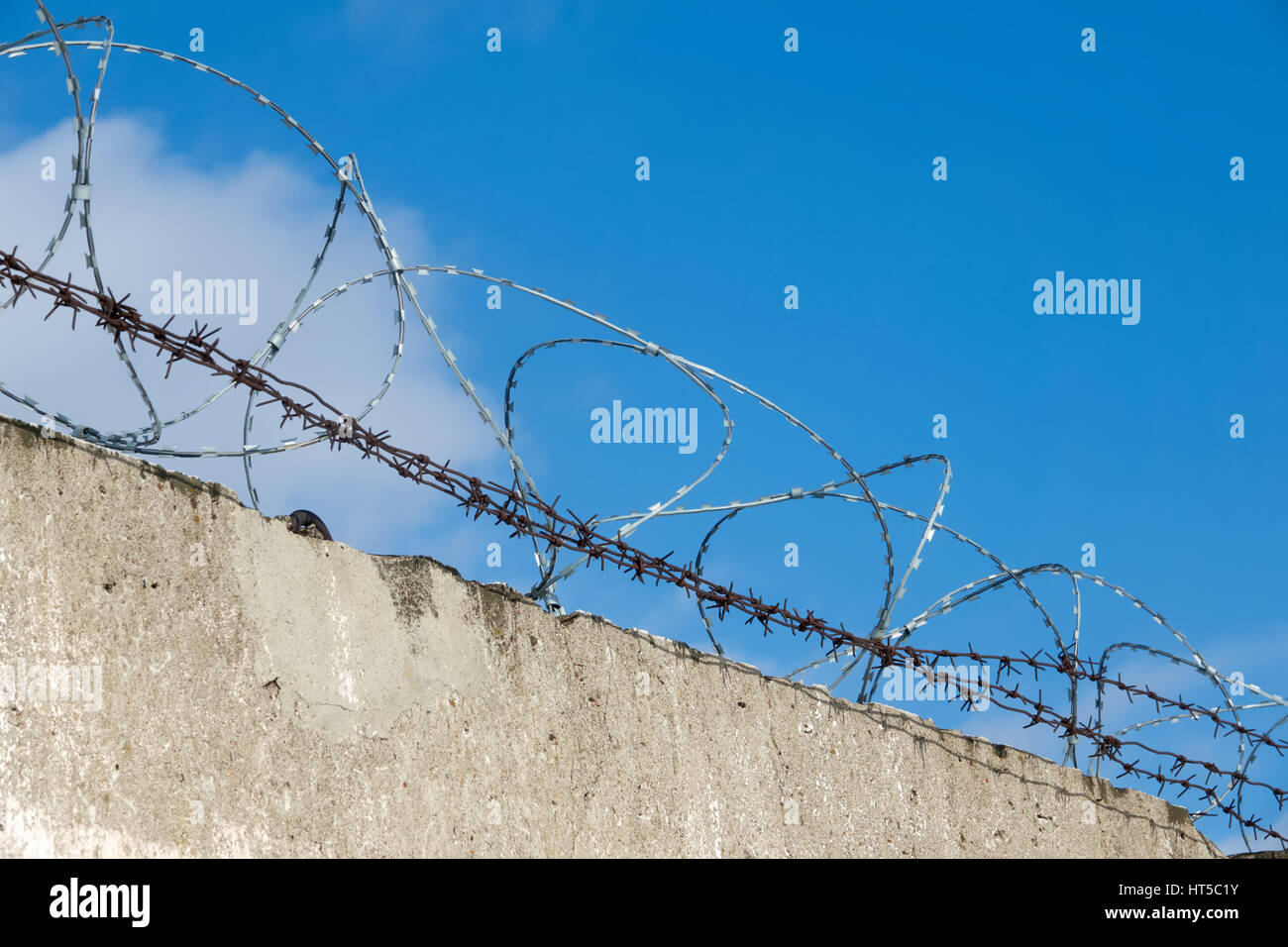 Fence with barbed wire. Blue sky. Clouds Stock Photo