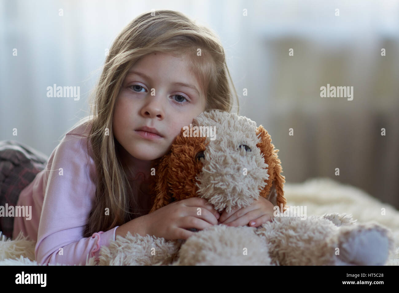 Sad girl with a toy dog on the bed Stock Photo