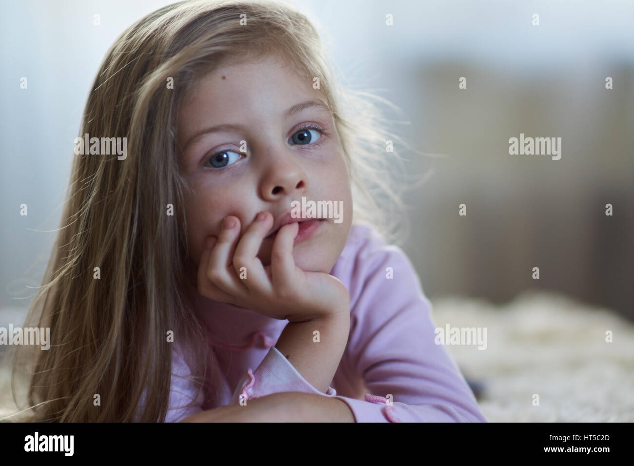 Sweet little girl with long hair on the bed Stock Photo