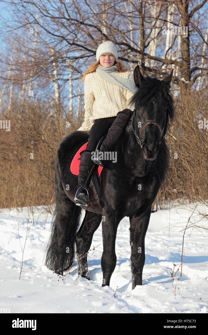 White blond girl riding horseback  in winter snow Stock Photo