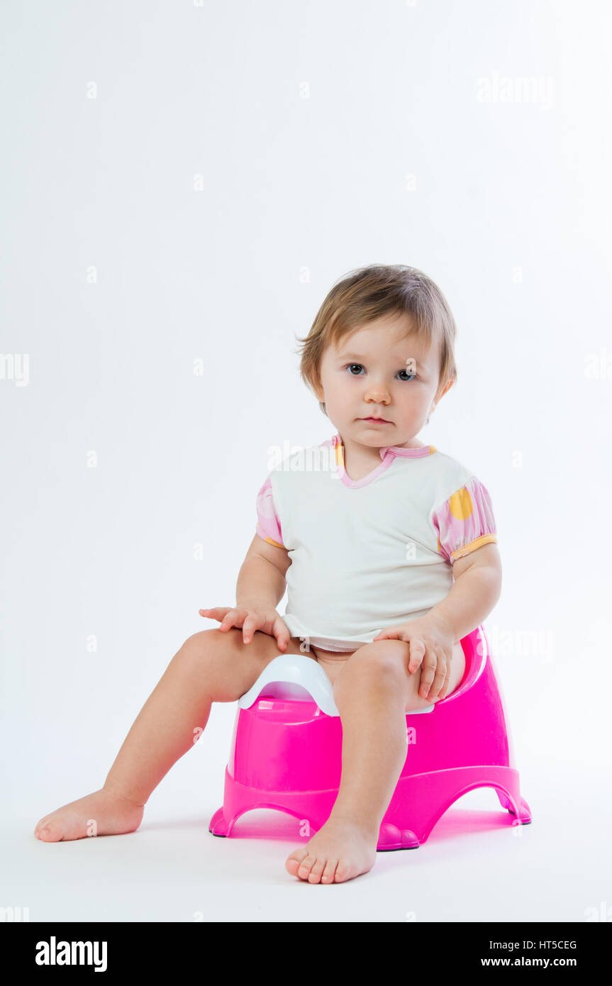 Little smiling girl sitting on a pot. Isolated on white background ...