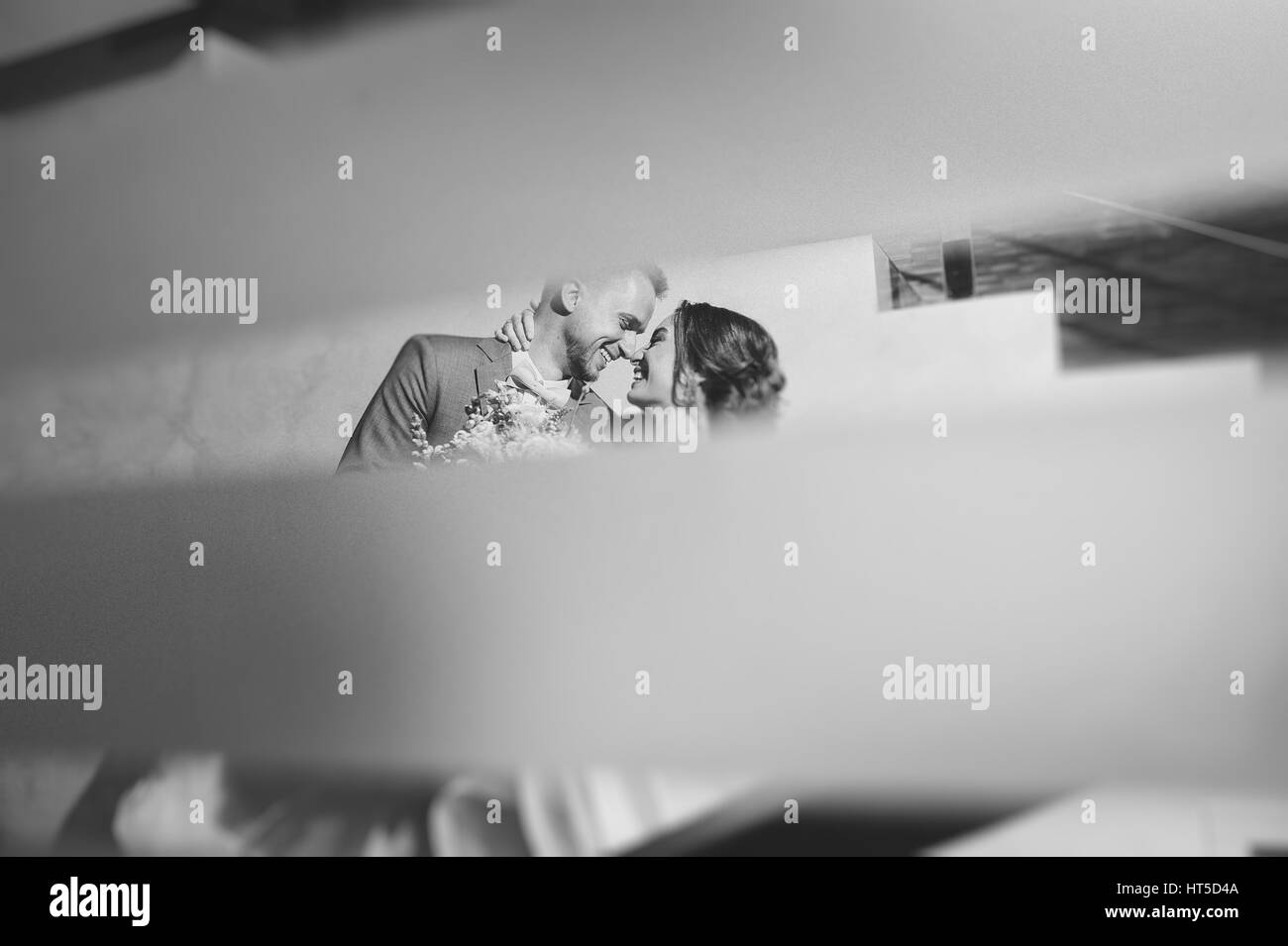 Portrait of a Happy newlyweds indoors. Bride and groom smiling. Bouquet in hand. Black and white photo. Stock Photo