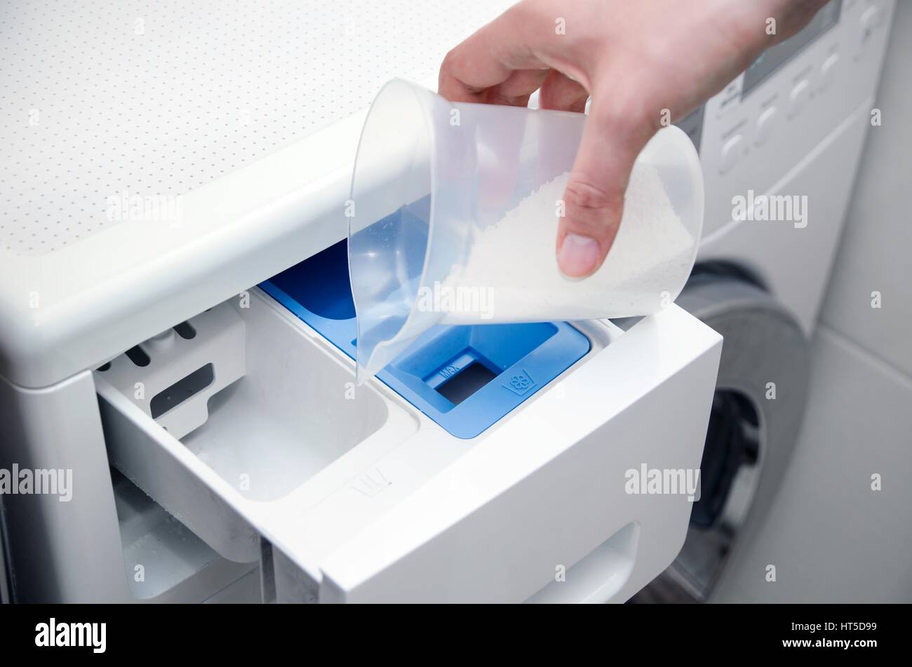 Woman hand pouring washing powder into the washing machine Stock Photo