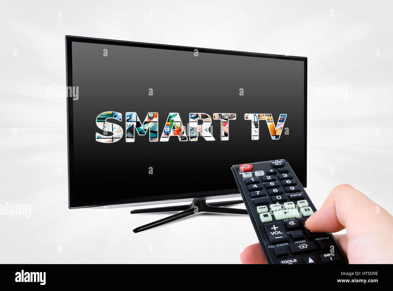 Hand with remote control aiming modern Smart TV device Stock Photo