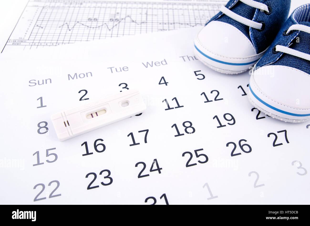 Positive pregnancy test on calendar and baby shoes Stock Photo