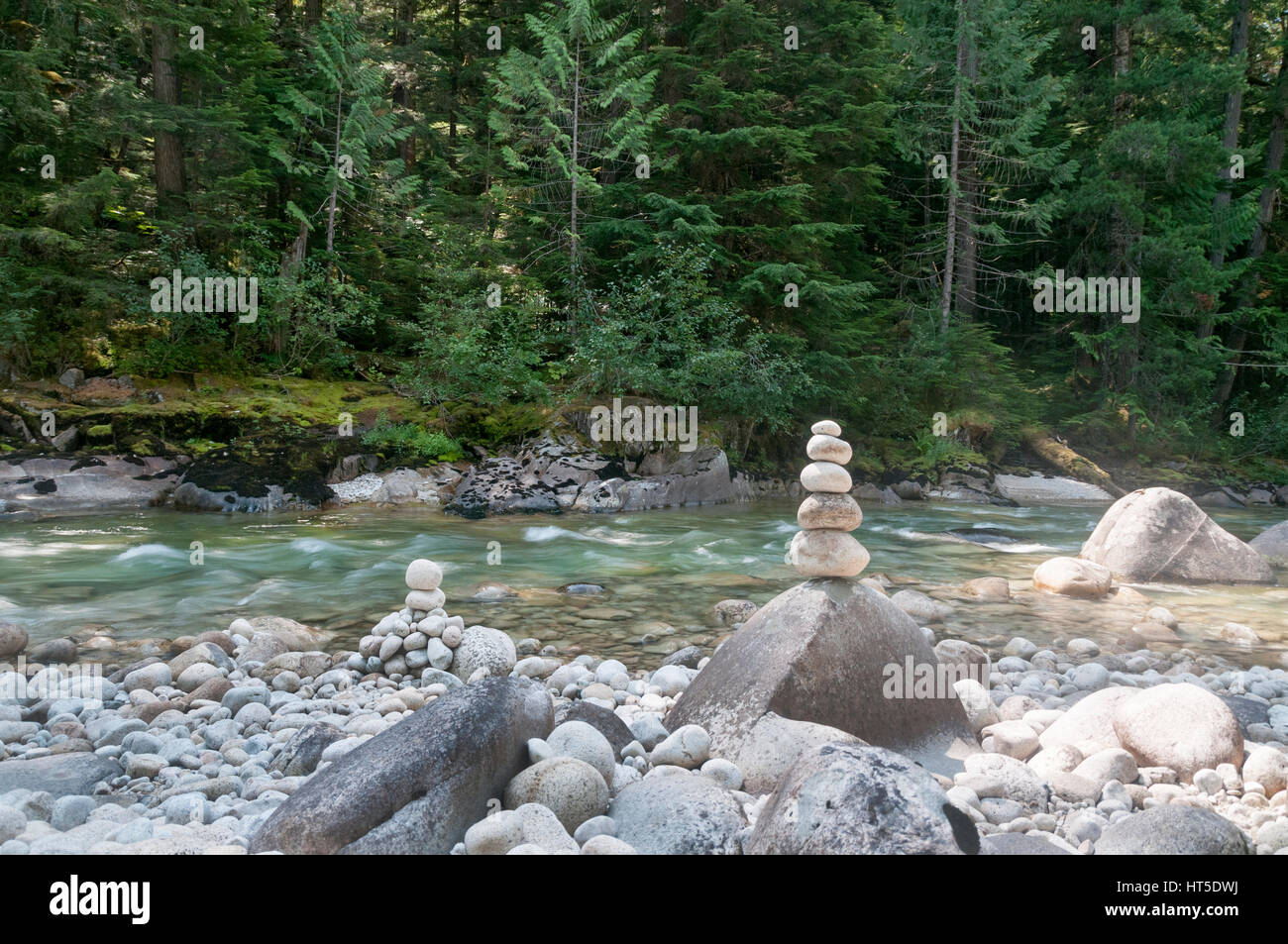 Stones stacked on a large rock beside a river in the forest Stock Photo