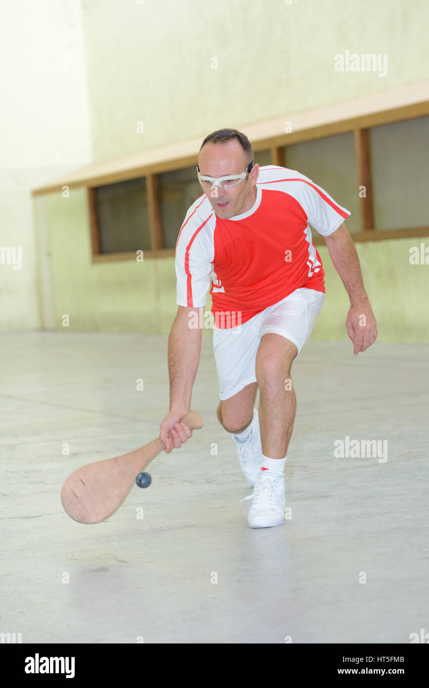 Sportsman reaching for ball with wooden racket Stock Photo - Alamy