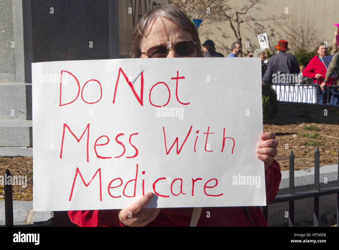 Asheville, North Carolina, USA - February 25, 2017:  Older woman holds a sign at an Affordable Care Act (ACA) demonstration telling politicians 'Do No Stock Photo