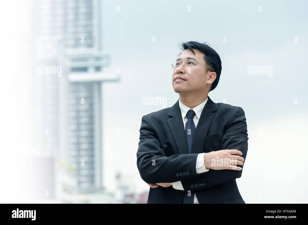 Portrait of asian businessman with arms crossed standing with city ...