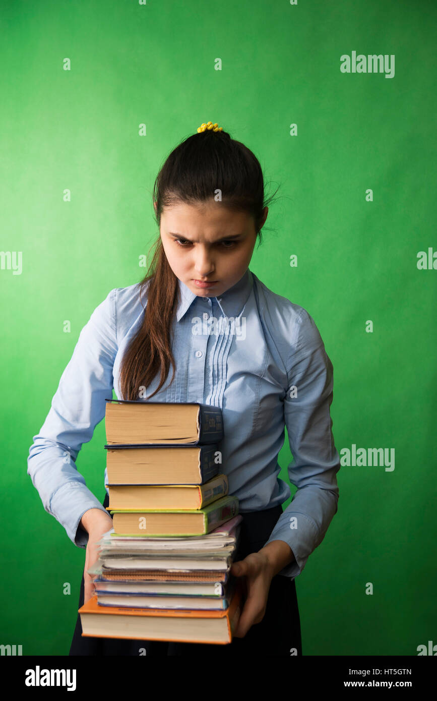 teen girl with long hair in the blue shirt holding a stack of books in his hands Stock Photo
