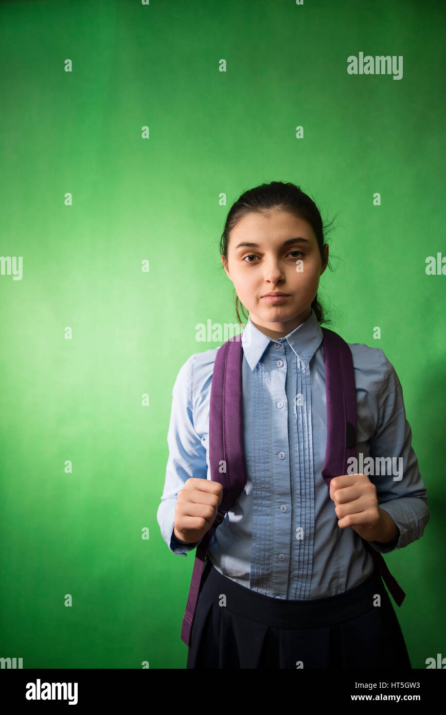 one teen schoolgirl in blue shirt is standing with a purple backpack on