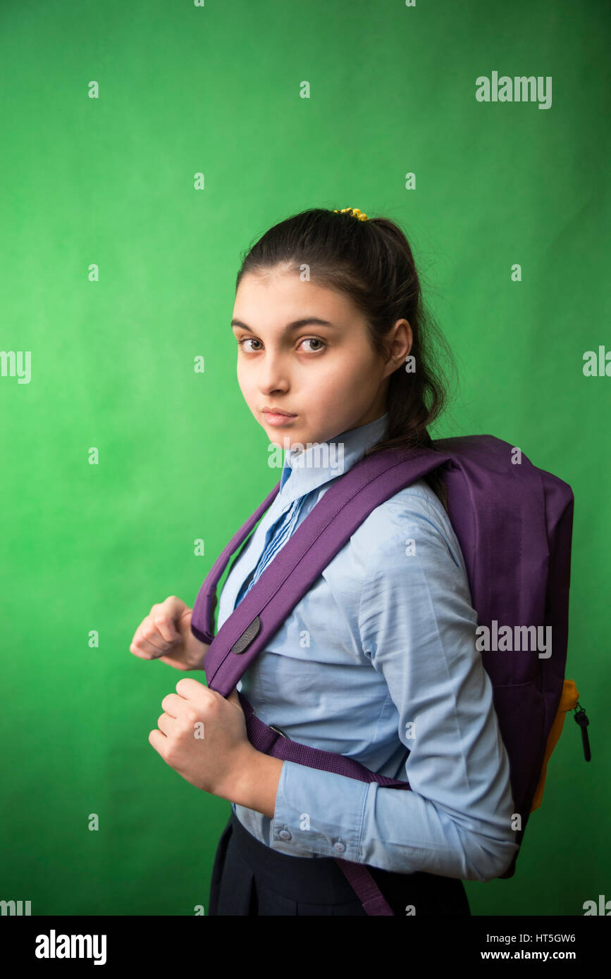 one teen schoolgirl in blue shirt is standing with a purple backpack on