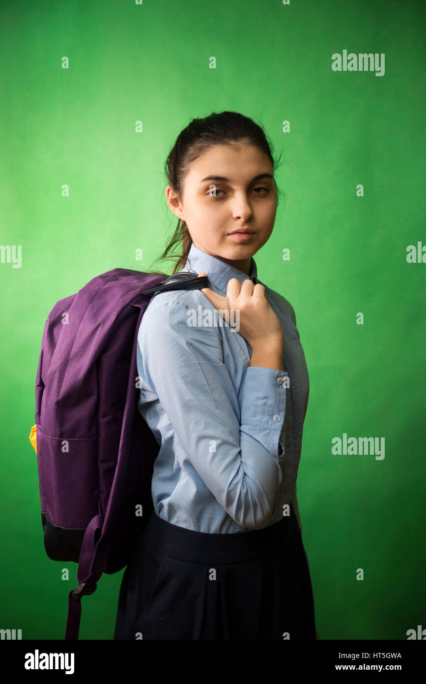 one teen schoolgirl in blue shirt is standing with a purple backpack on