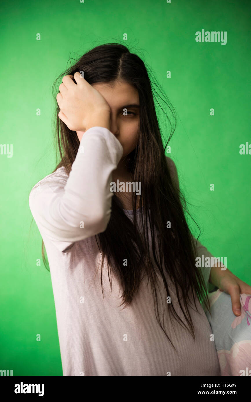 girl in her nightie wants to sleep and rubs his eyes on a green background isolated chroma key Stock Photo