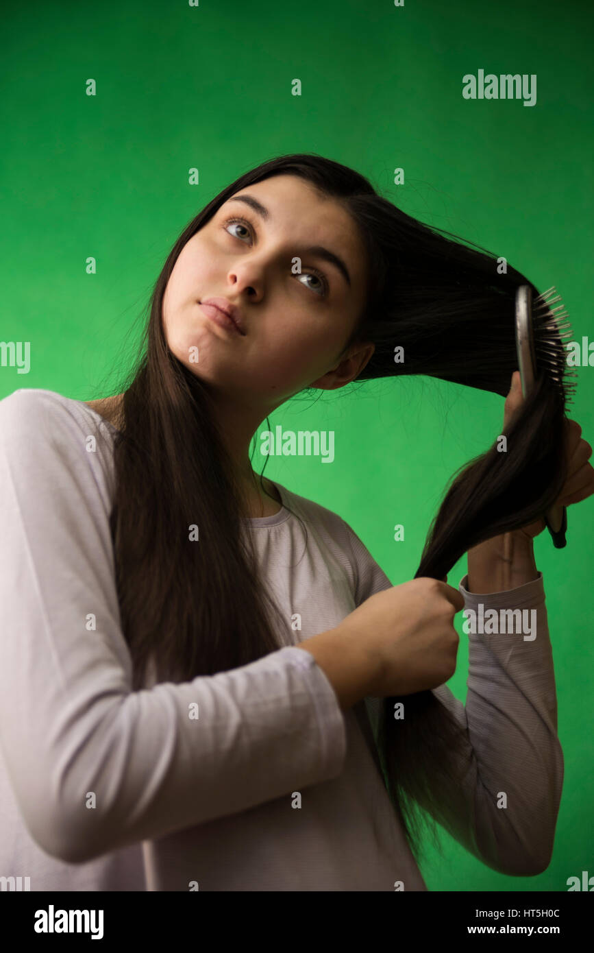 teen girl in nightie comb hair at green chroma key background Stock Photo