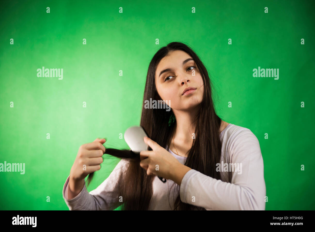 teen girl in nightie comb hair at green chroma key background Stock Photo
