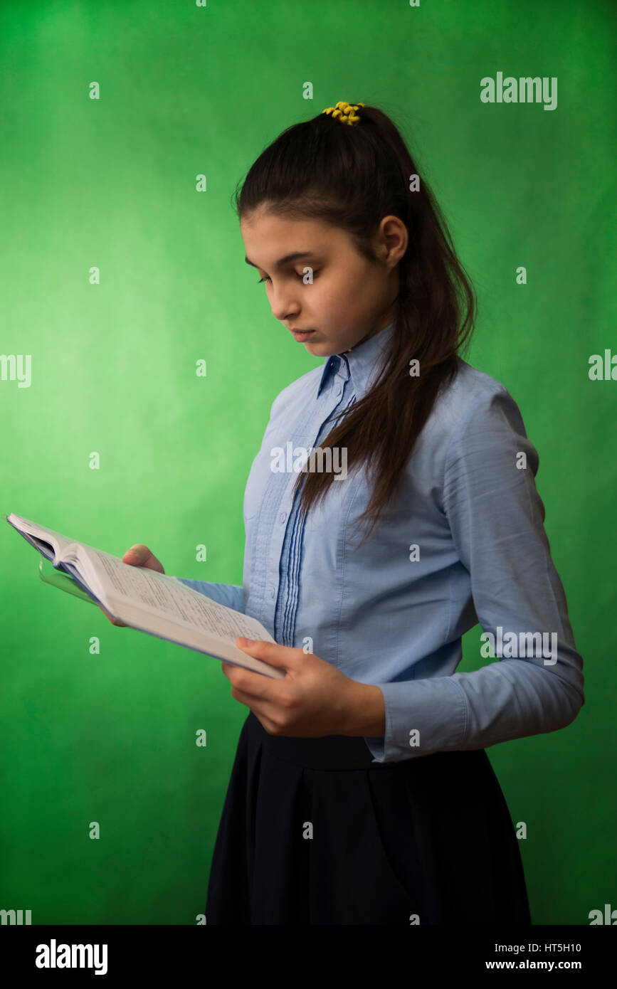 teen girl with long hair in the blue shirt holding a stack of books in his hands Stock Photo
