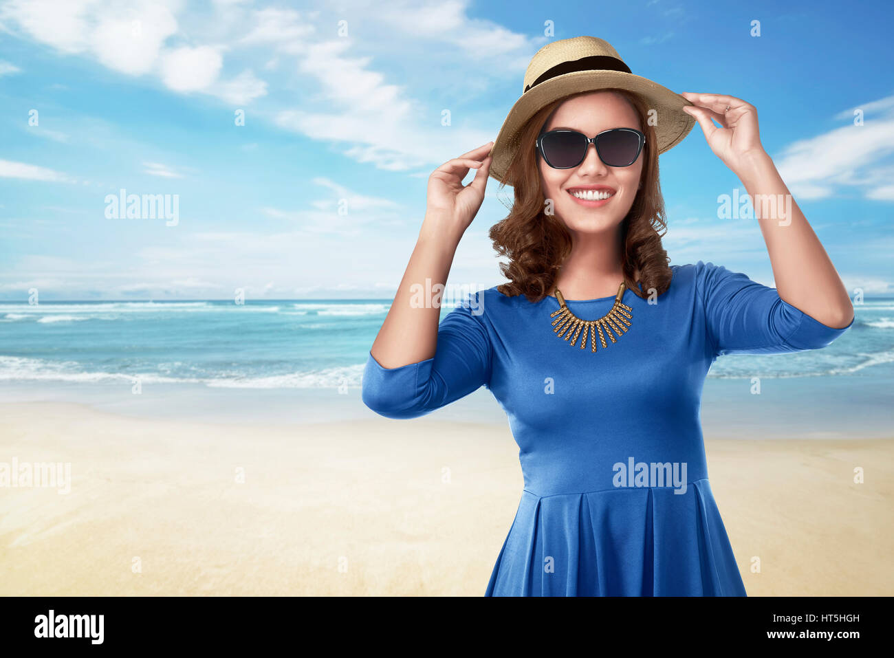 Beautiful asian woman with black eyeglasses holding hat on the beach Stock Photo