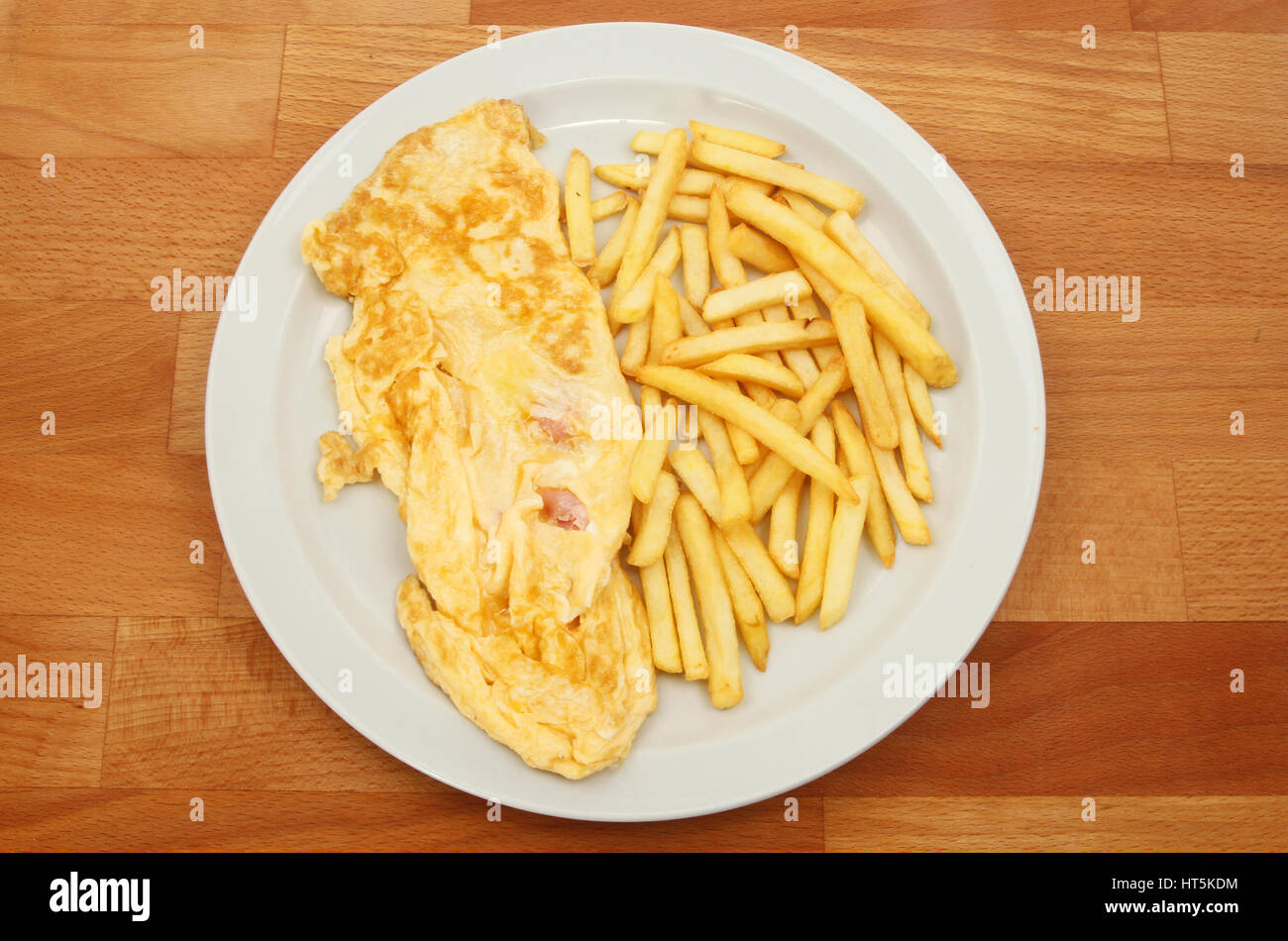 Ham and cheese omelette with French fries on a plate on a wooden tabletop Stock Photo