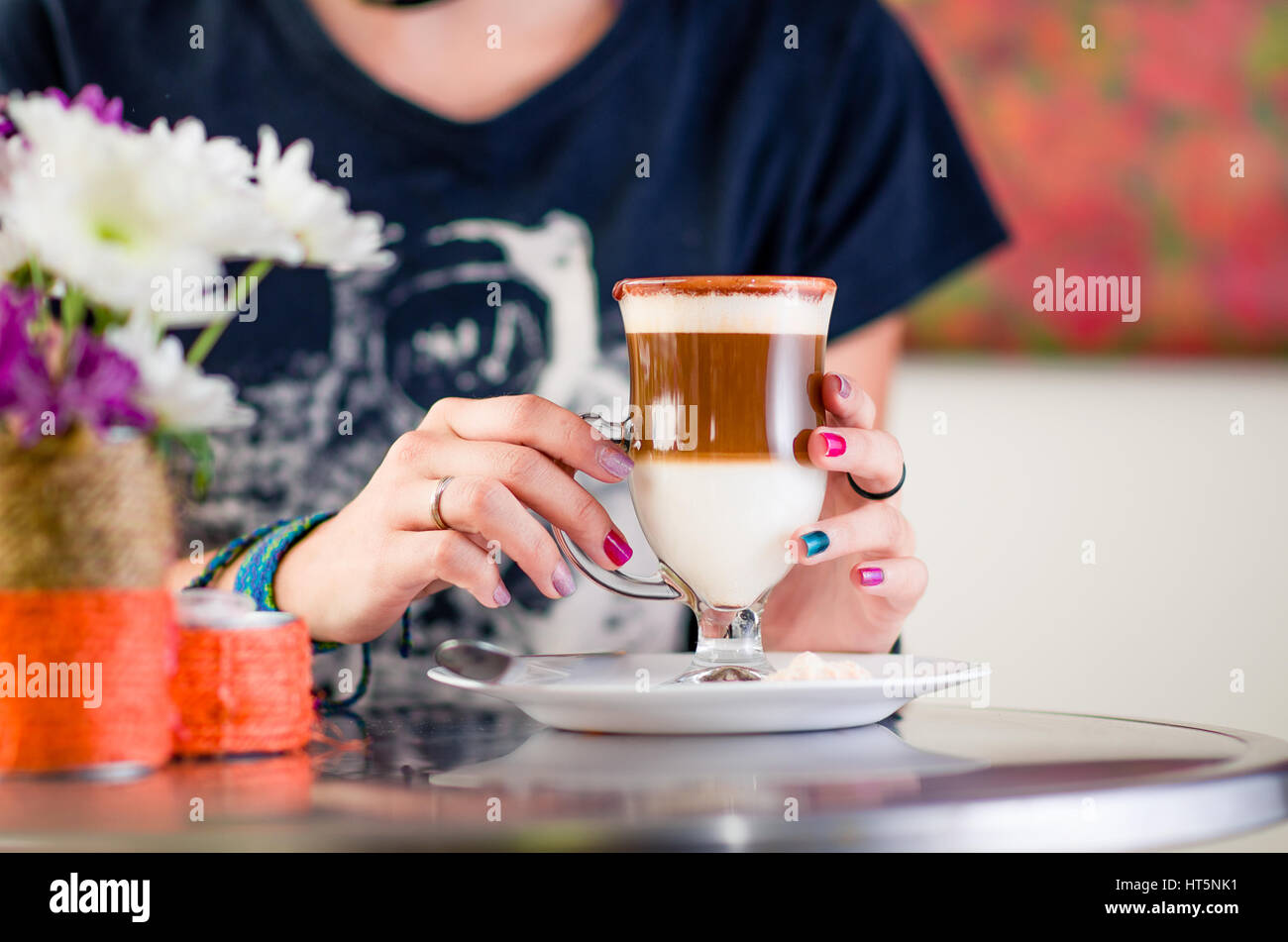 Girl drinking cappuccino inside an art cafe while reading a book Stock Photo