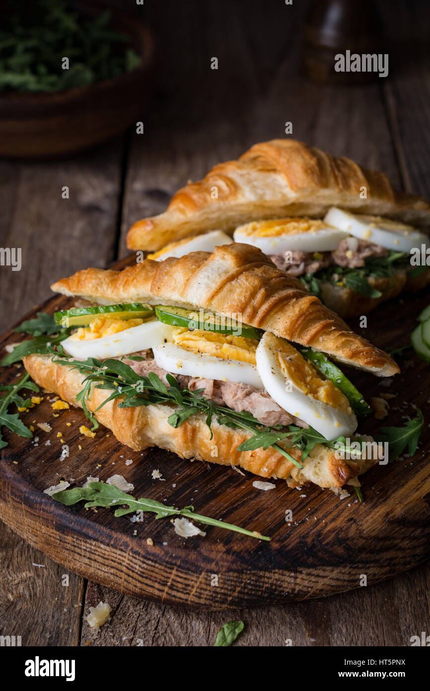 Tuna salad sandwich with boiled egg, arugula, cucumber and tuna salad on wooden cutting board. Closeup view, selective focus Stock Photo