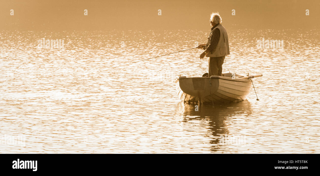 Mature man fly fishing from boat on Lockwood Beck, North York Moors National Park, North