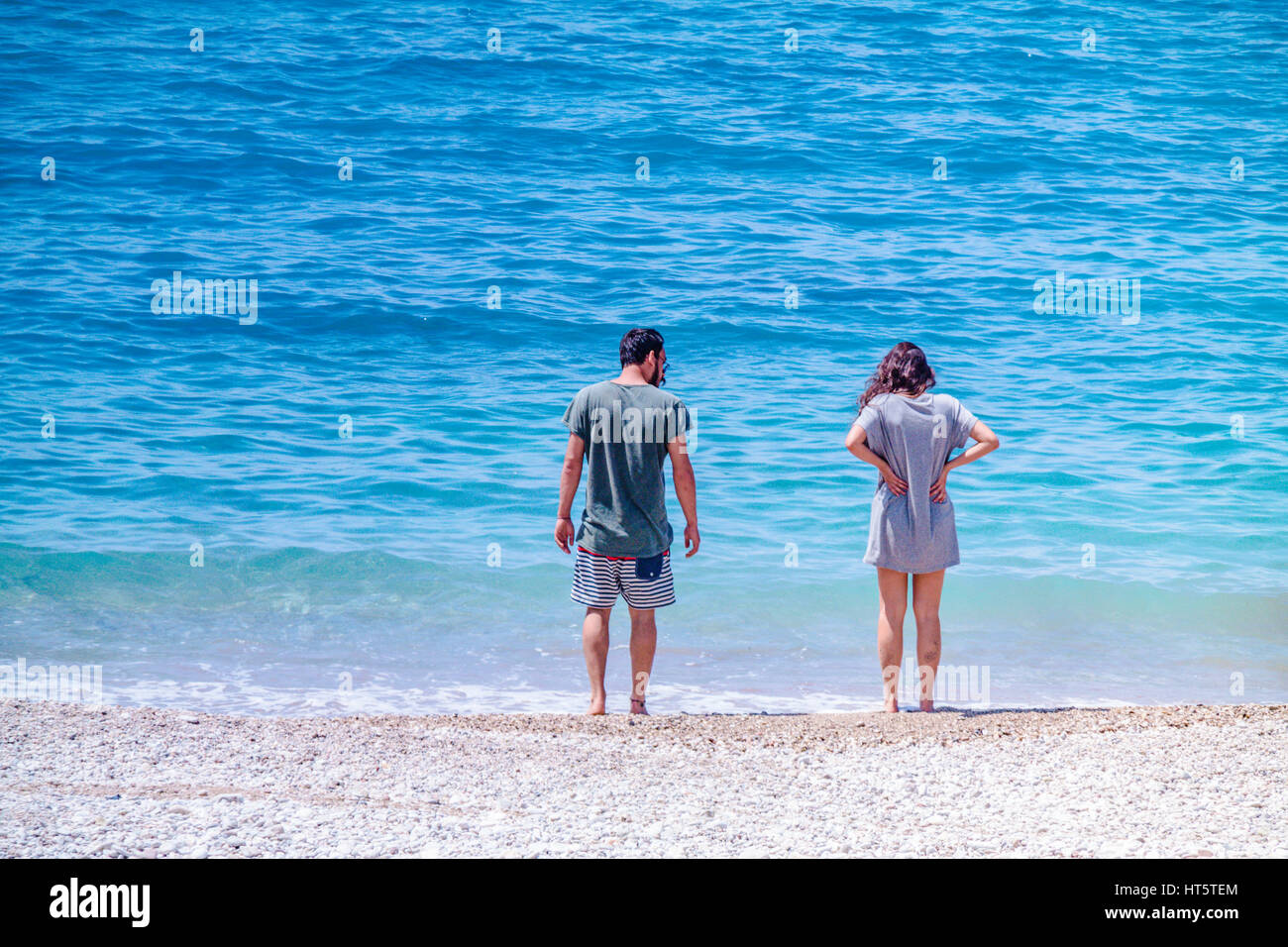 couple on the beach walking to the sea with clothes Stock Photo