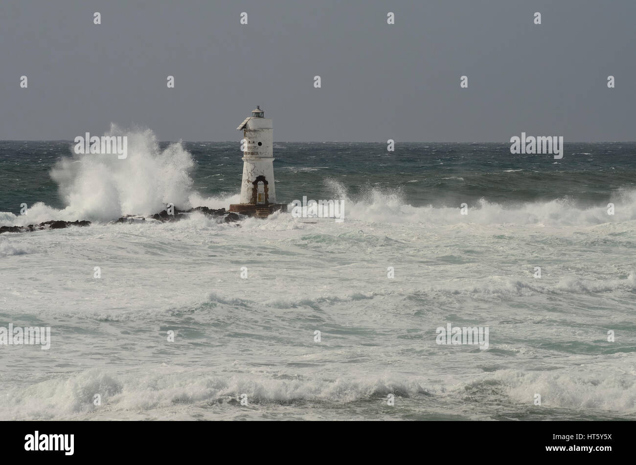 Lighthouse in the wind, white wave in the left, grey sky, white water. Stock Photo