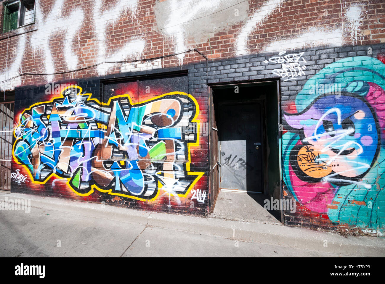 A graffiti covered wall and doorway on a building in a back alley of Kensington Market in Toronto Ontario Canada. Stock Photo