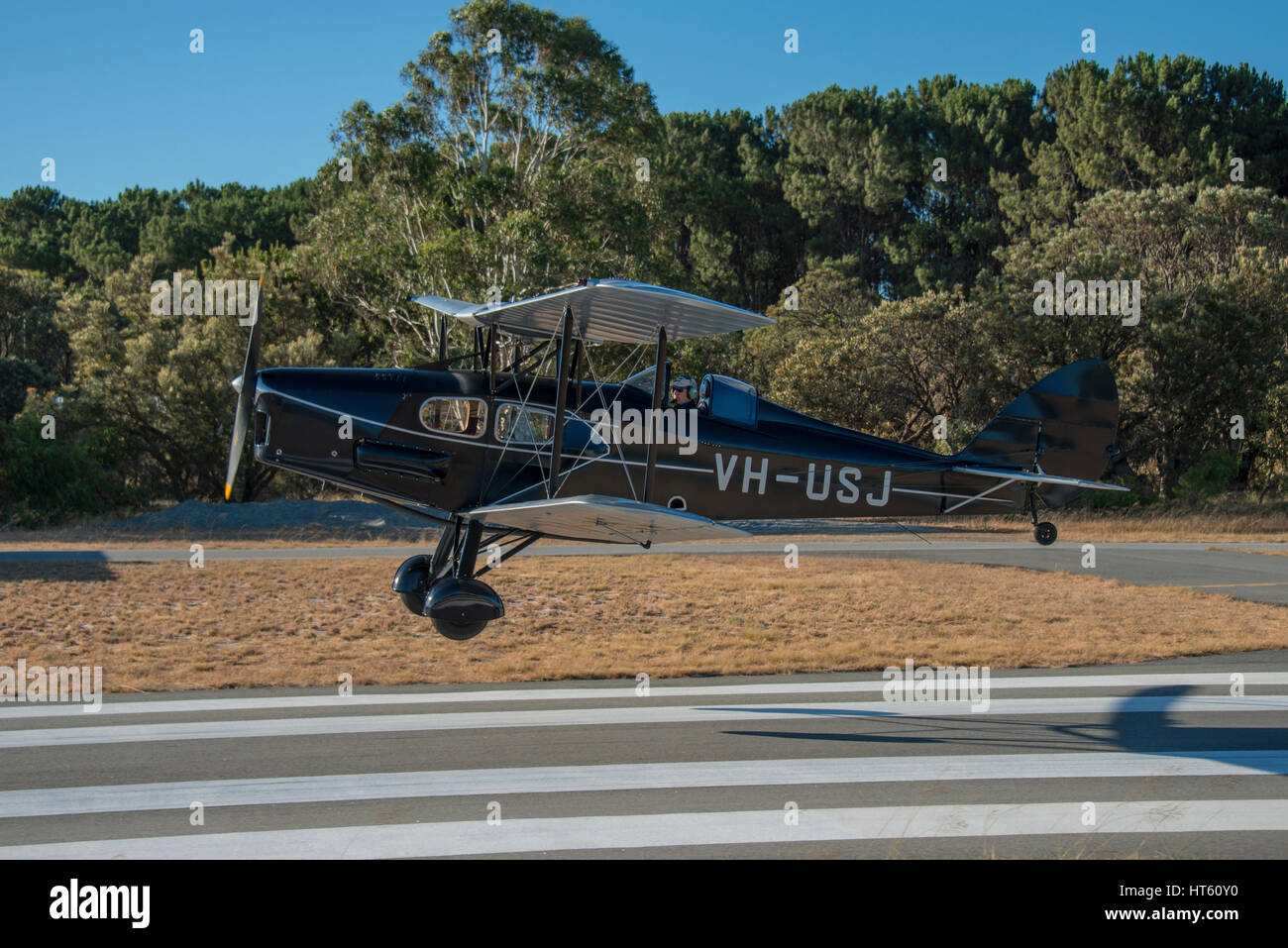 side view of a DH Fox Moth biplane lifting off the runway Stock Photo