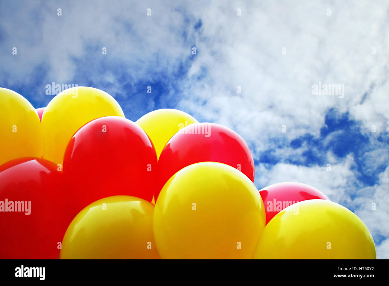 Many bright shiny yellow and red balloons against the blue sky Stock ...