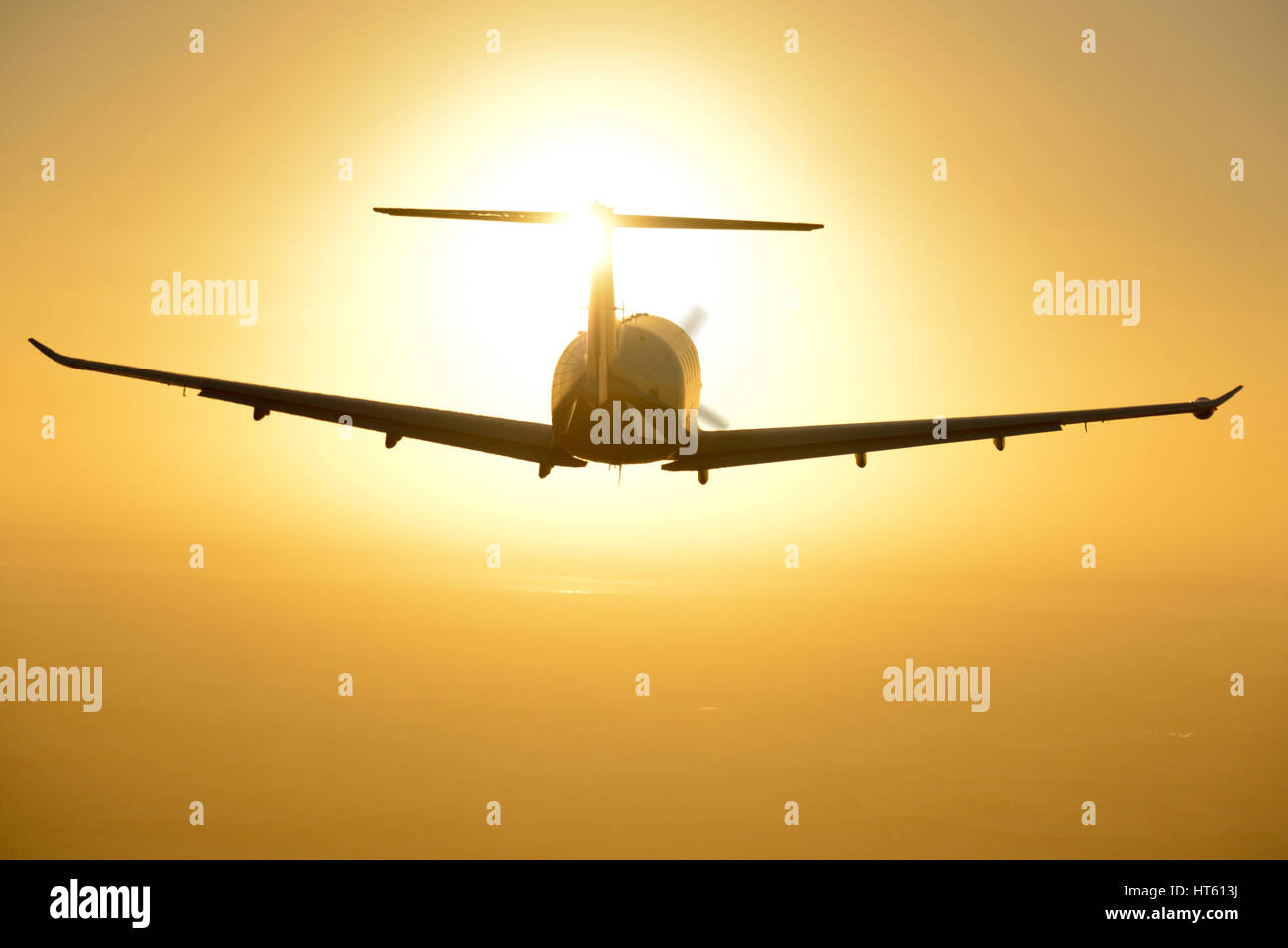 An air to air shot of a pilatus PC12 aircraft silhouetted against the sunset Stock Photo