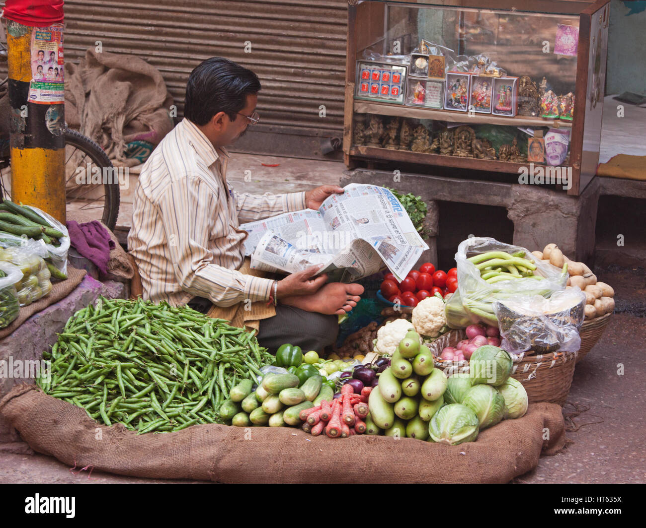 Vegetable seller taking a break to catch up with current affairs in his paper in the Chandni Chowk area of old Delhi, India Stock Photo