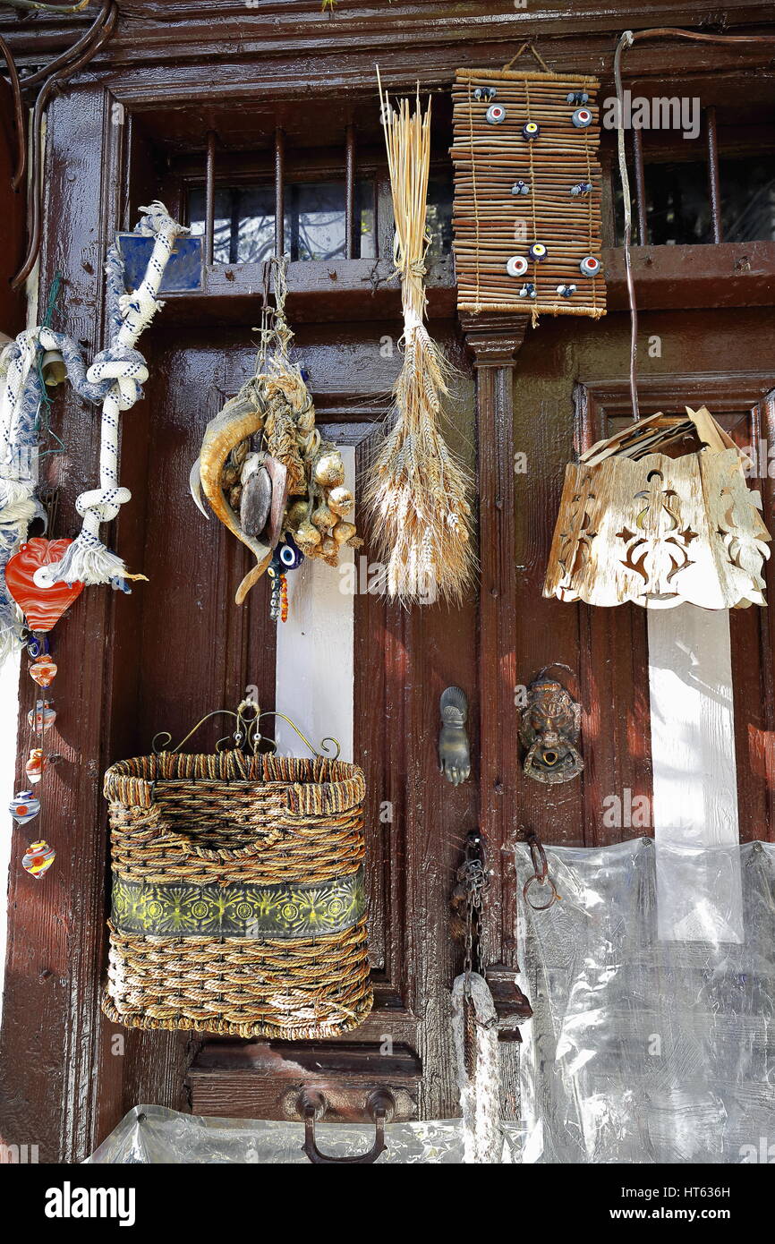 Old wooden door plenty of nazar boncugu-blue bead eye shaped amulets and miscellaneous items of wicker-wood-straw hanging on it. Street in the old are Stock Photo