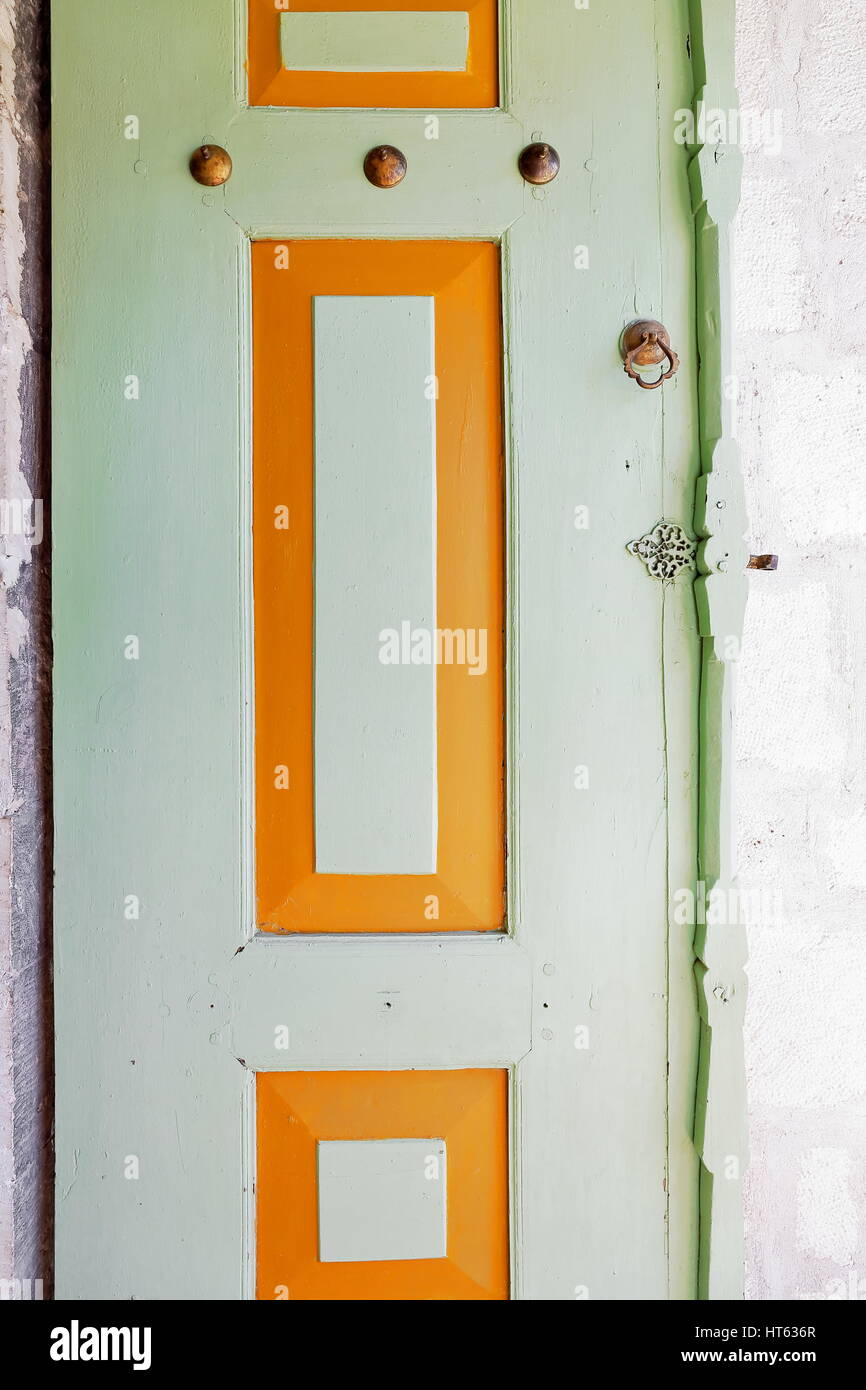 Detail of green and orange painted wood window shutter with tin tack