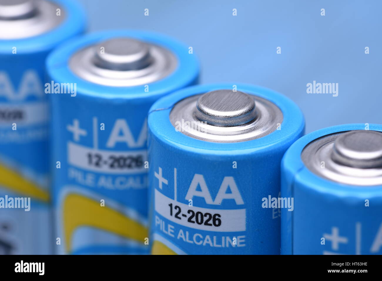 Group of AA alkaline batteries used in many household item, close up on a blue metal mackground