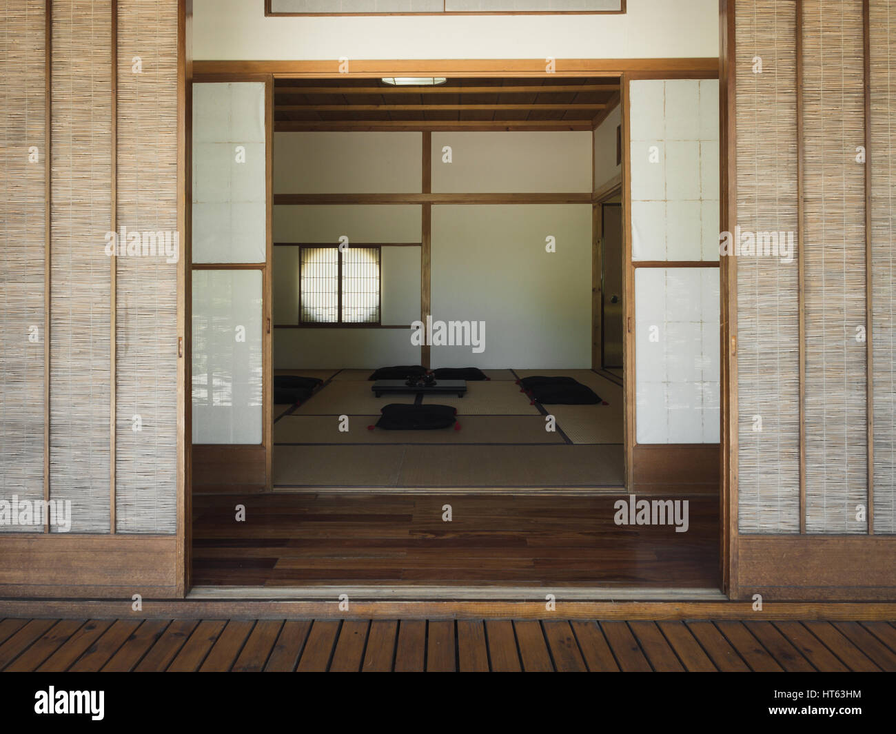 Photography of the entrance sliding doors of an empty Japanese tea room with some pillows on the ground. Stock Photo