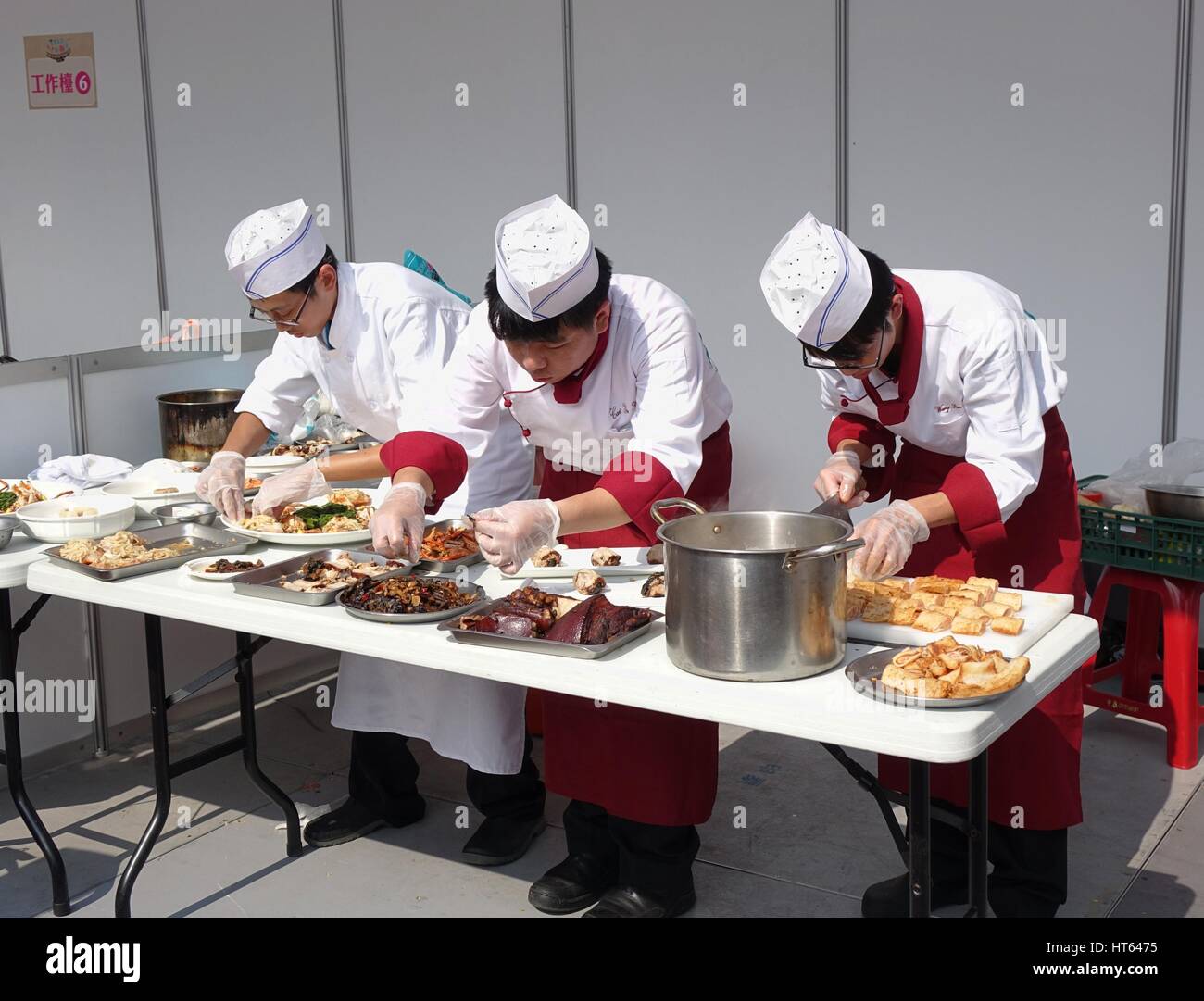 KAOHSIUNG, TAIWAN -- NOVEMBER 28, 2015: Three chefs prepare dishes for the cooking competition during the 2015 Hakka Food Festival, which is a yearly  Stock Photo