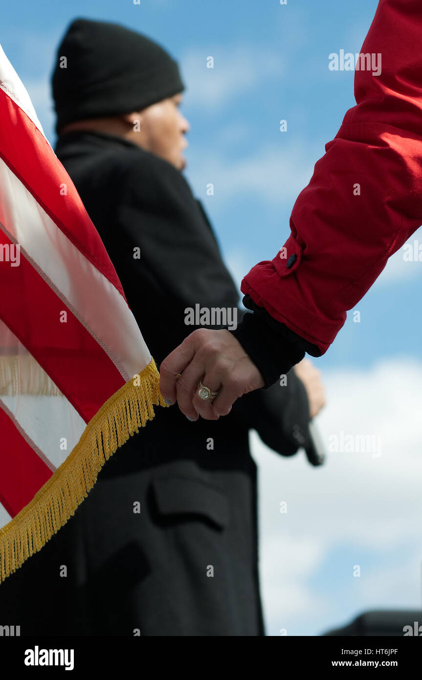 At the start of a pro-trump rally as the National Anthem is performed MC Erin Elmore holds a tip of the American flag, in Bensalem, PA, on March 4th,  Stock Photo