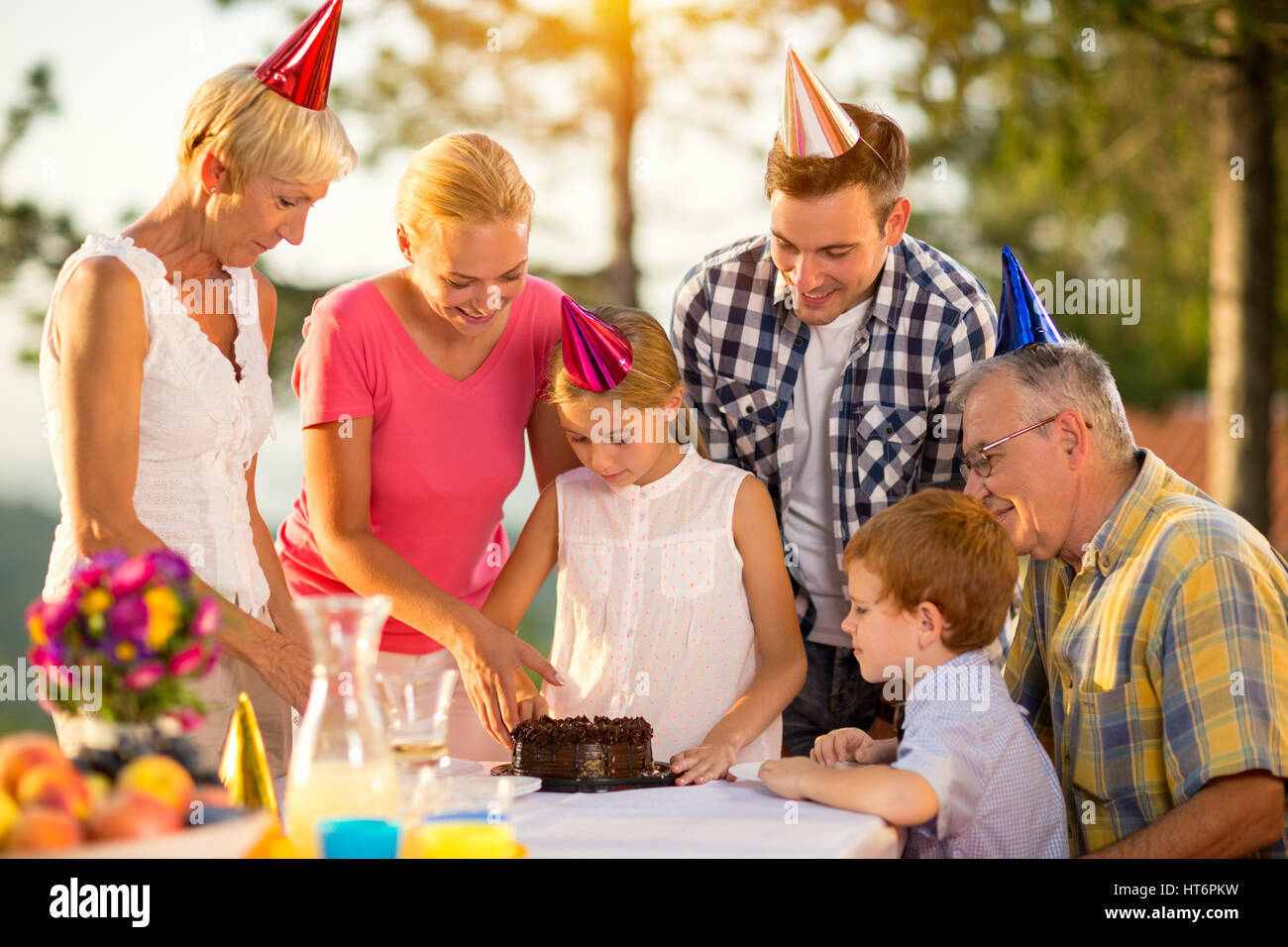mother helping female child with birthday cake Stock Photo