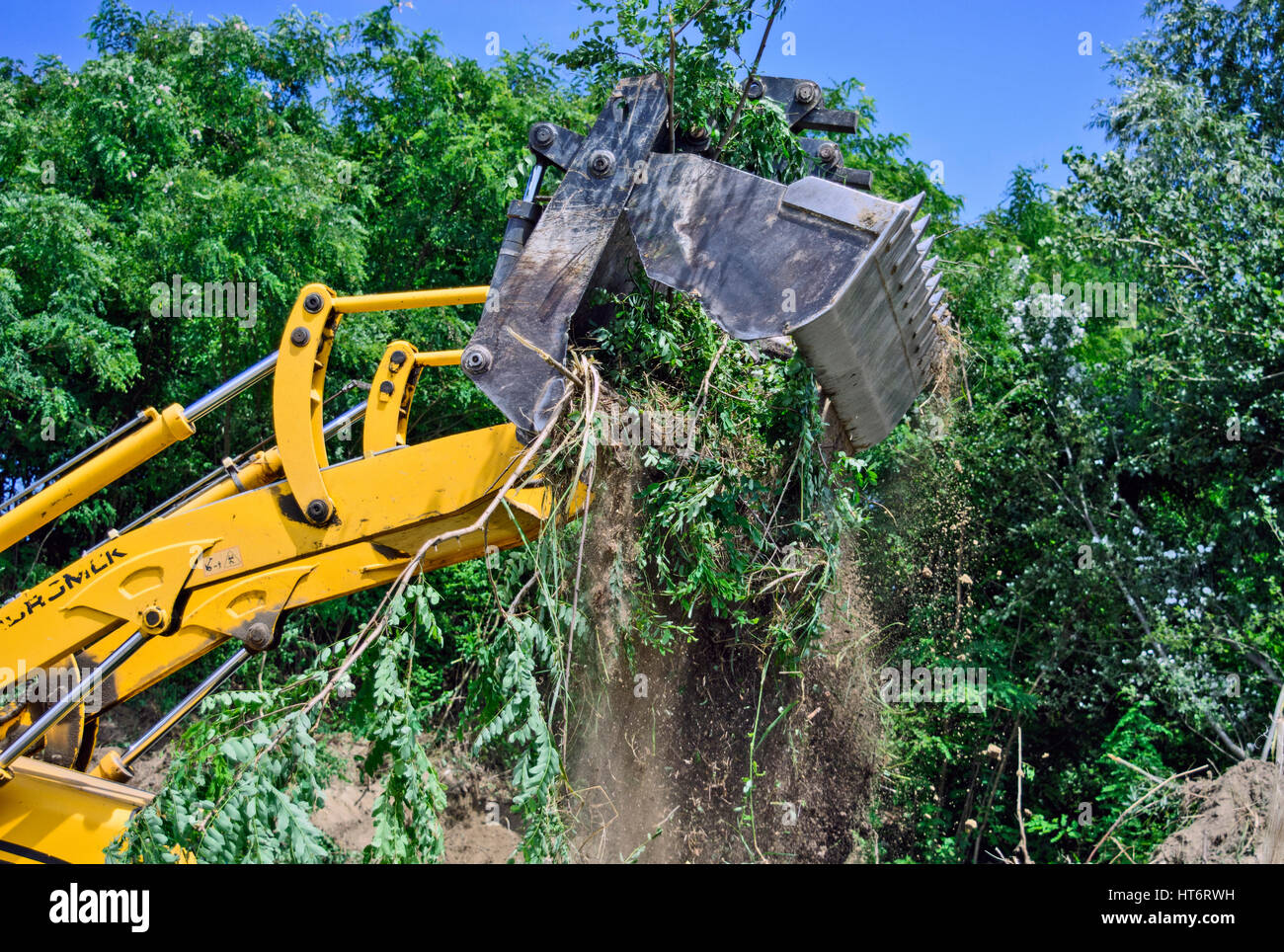 Excavator with bucket loading sand and rubble for removal. Stock Photo