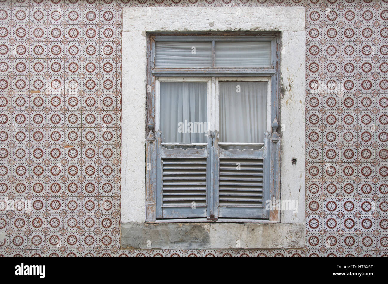 Window of a house with worn wooden shutters, surrounded by traditional