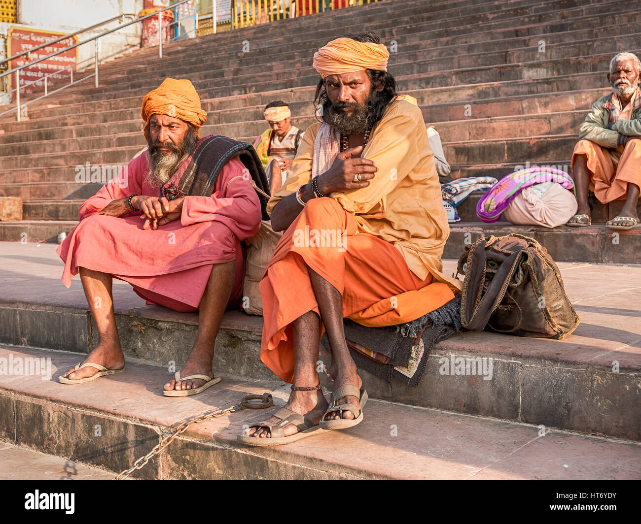 RISHIKESH, INDIA - NOVEMBER 16, 2016: Two sadhus, or holy men, sit in colorful attire the steps of a ghat near the Ganges River in the holiy city of R Stock Photo