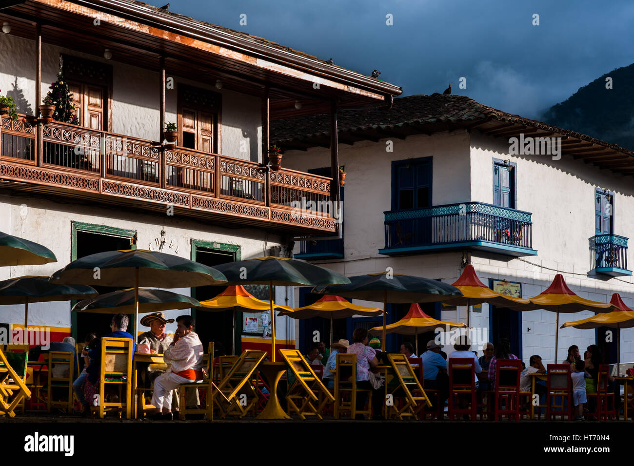 Colombian peasants sit in a coffee-shop in front of the colonial houses at the main plaza of Jardín, a village in the coffee region in Colombia. Stock Photo
