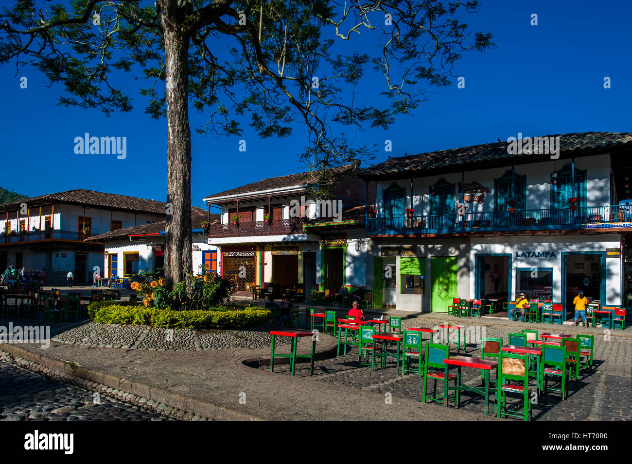 Colombian peasants sit in a coffee-shop in front of the colonial houses at the main plaza of Jardín, a village in the coffee region of Colombia. Stock Photo