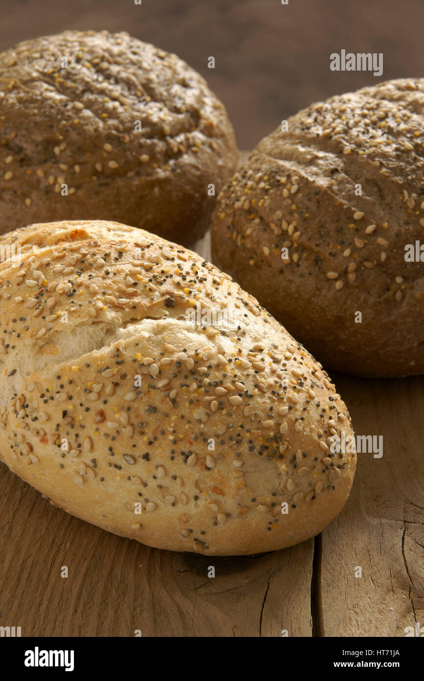 Rustic wholegrain loaves on a wooden bread board Stock Photo